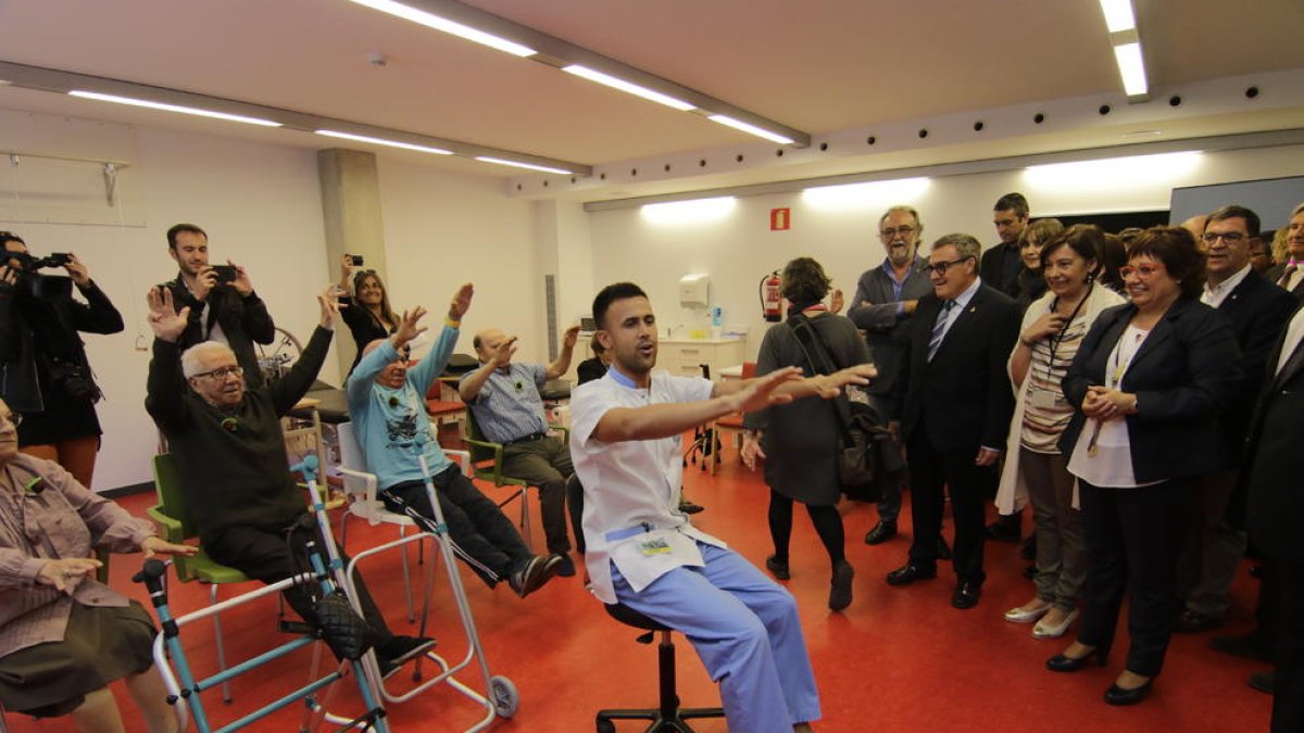 Usuarios de la nueva residencia hacen gimnasia  ante las autoridades en la sala de fisioterapia.