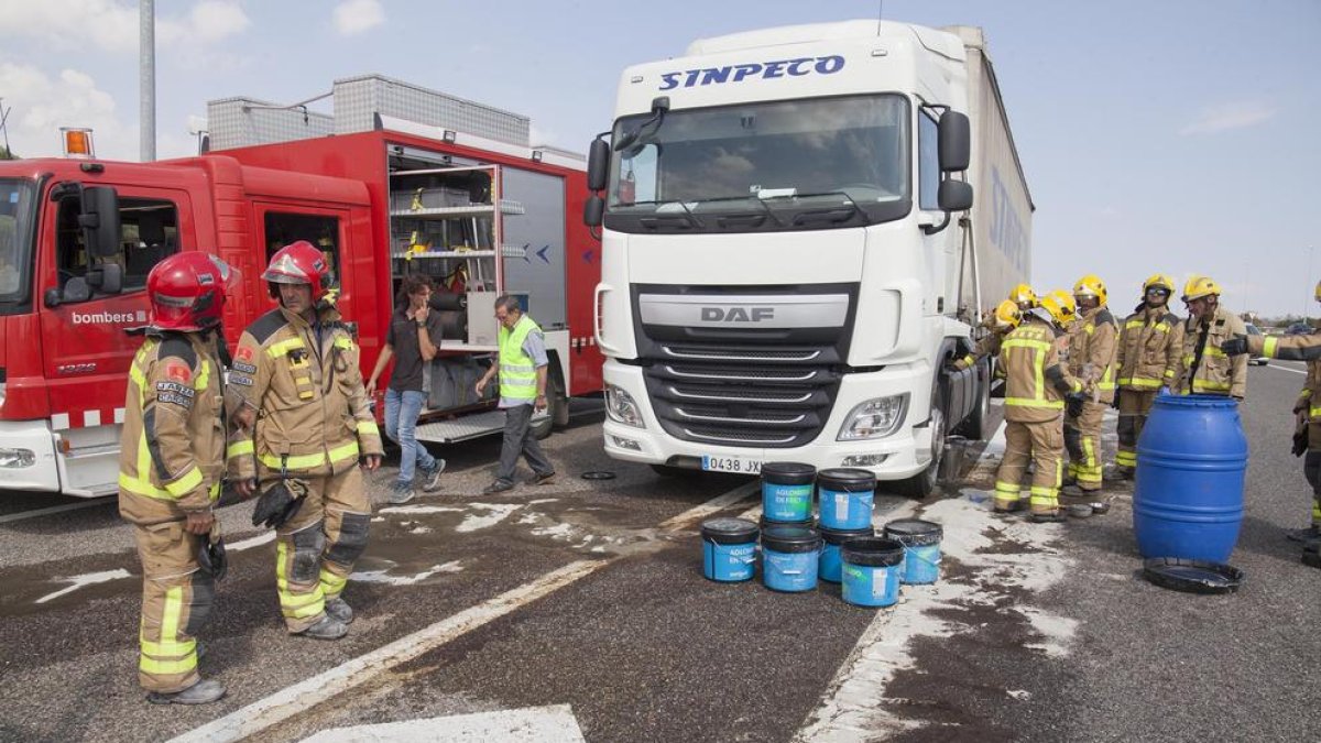Els bombers van retirar amb cubells el combustible del camió després de l’accident a Ribera d’Ondara.