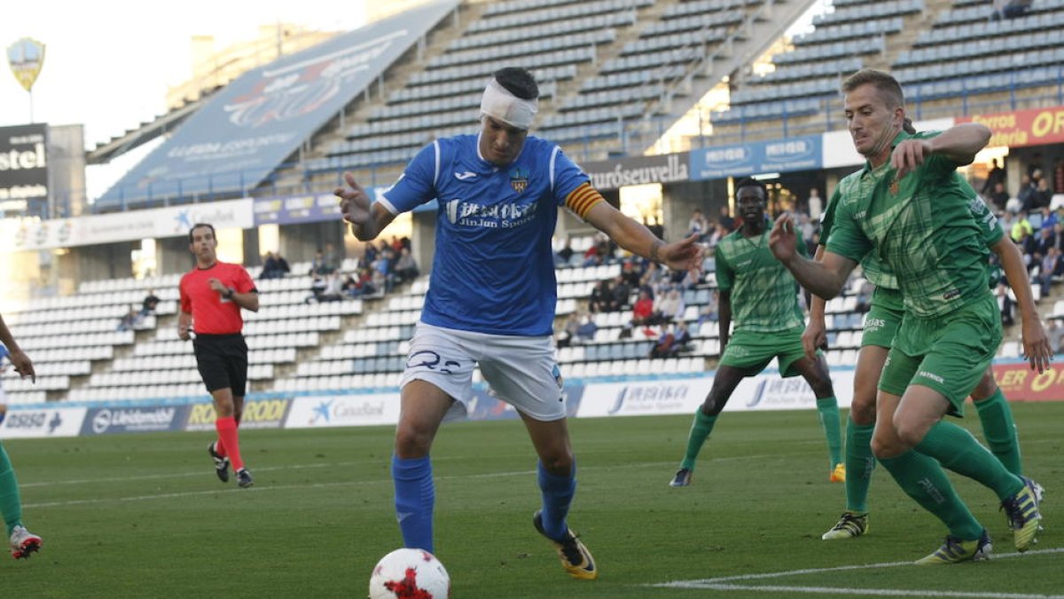 El davanter Marc Nierga, que va jugar des de la primera part amb un aparatós embenat al cap, intenta rematar davant l’oposició de defenses del Cornellà.