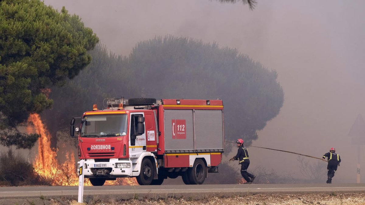 Imagen de dos bomberos luchando contra las llamas.