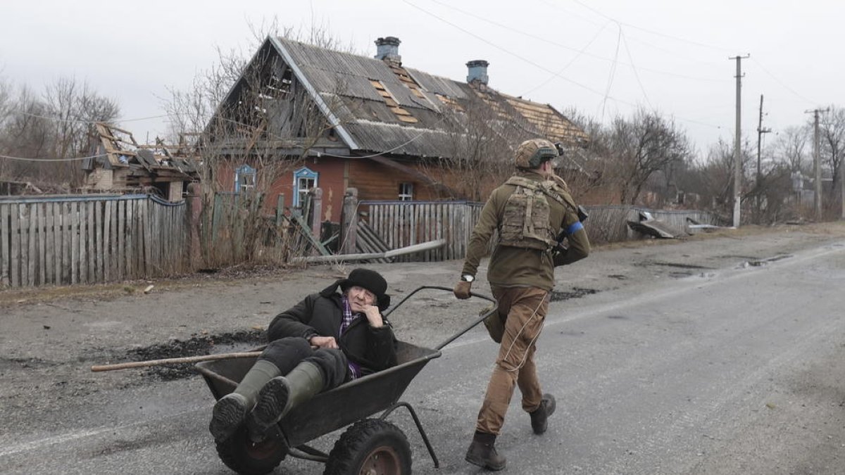 Un soldat ucraïnès porta una dona en un carro.