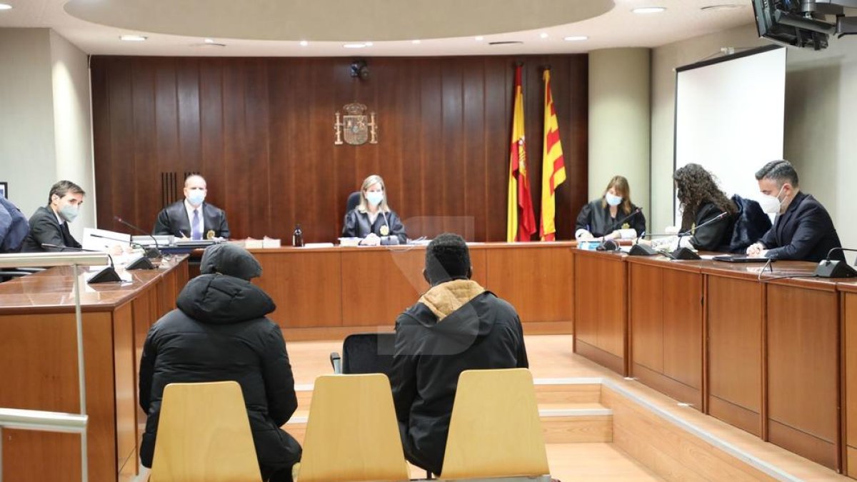 La Sala de la Audiencia de Lleida durante el juicio a un acusado (izquierda) de agredir sexualmente a la hija, con el traductor (derecha).