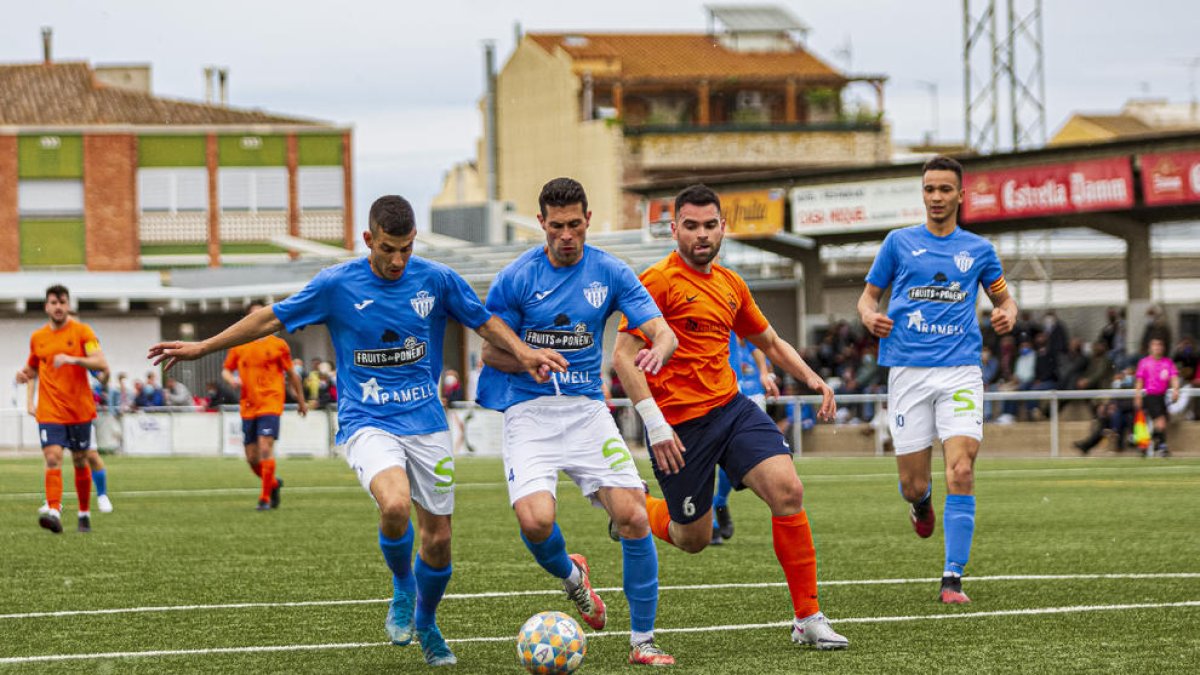 Dos jugadores del Alcarràs cortan el avance de un rival del Atlètic Lleida.