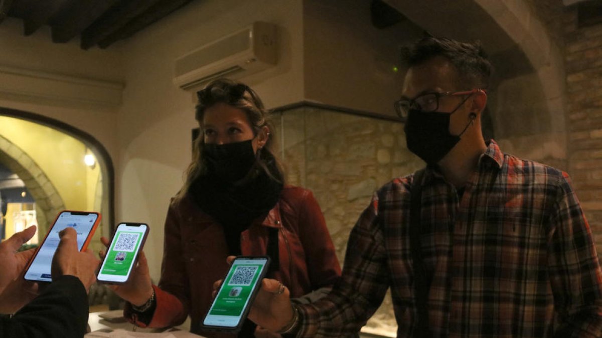 Dos persones mostren el seu certificat ‘Covid free’ en un restaurant.