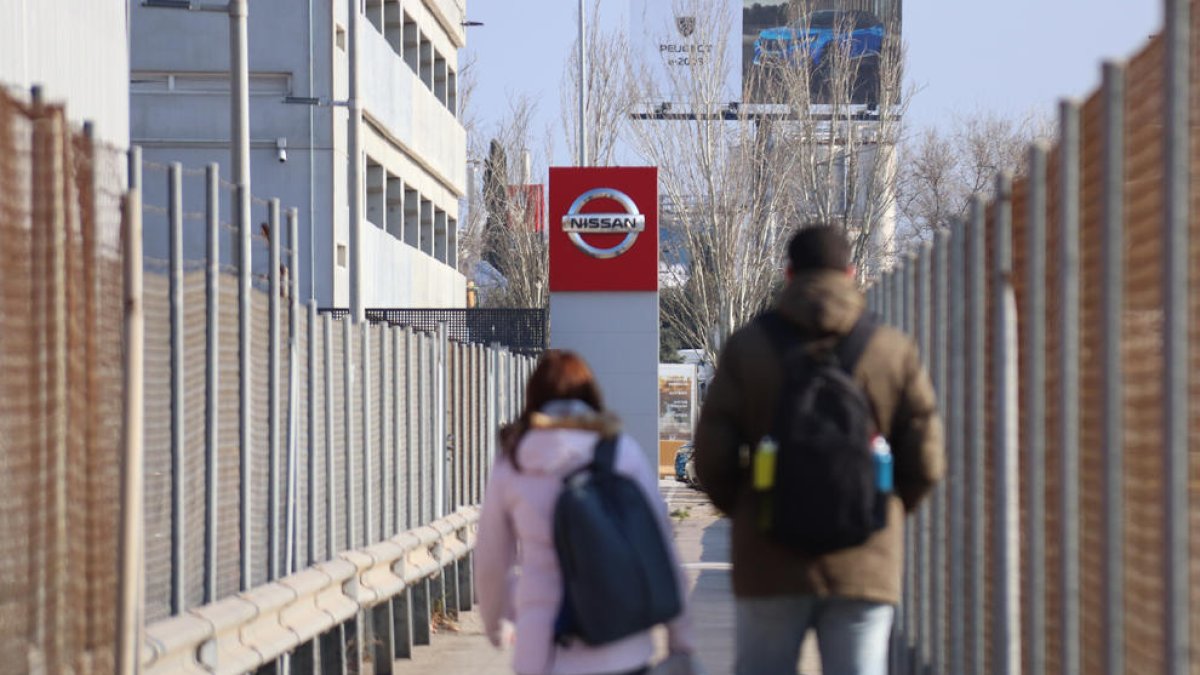 Dos persones surten de la fàbrica de Nissan a la Zona Franca.