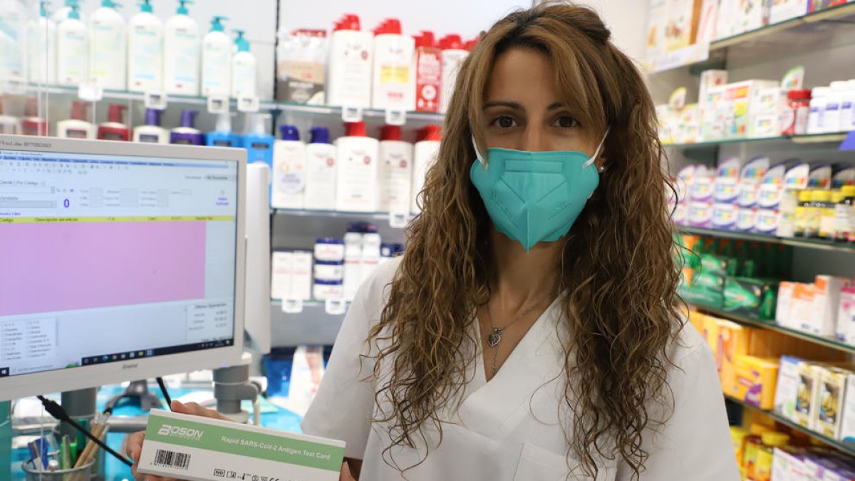 Una treballadora de la farmàcia Garrós de Lleida mostra un test d’antígens.