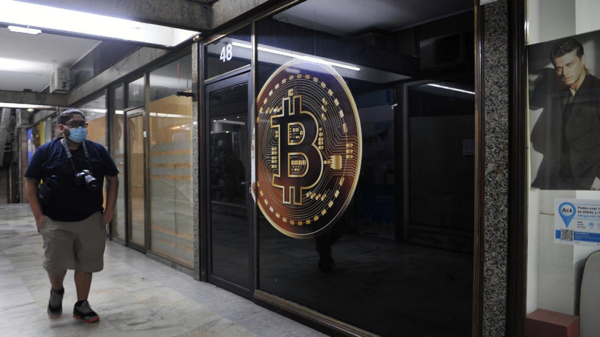 Un home camina davant una botiga de criptomoneda.
