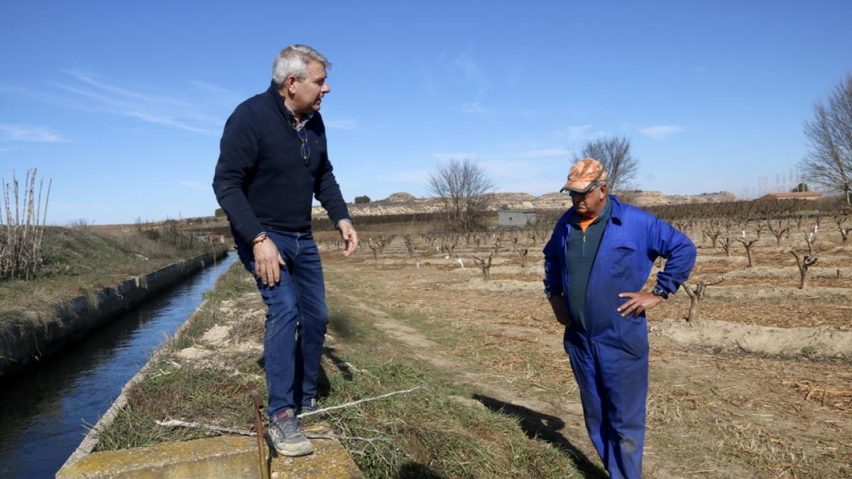 Los dos vecinos de Aitona muestran cómo se riega ‘a manta’ los campos que aún no se han modernizado.