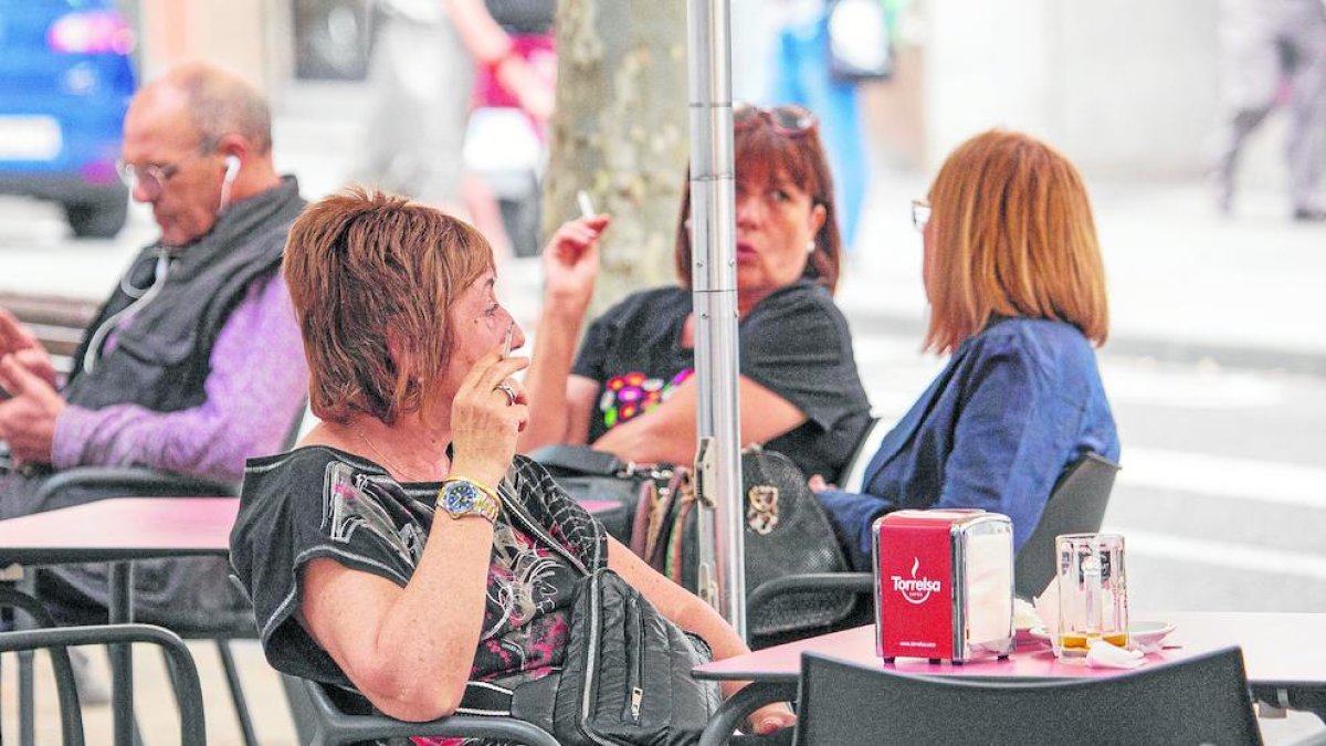 Personas fumando en la terraza de un bar.
