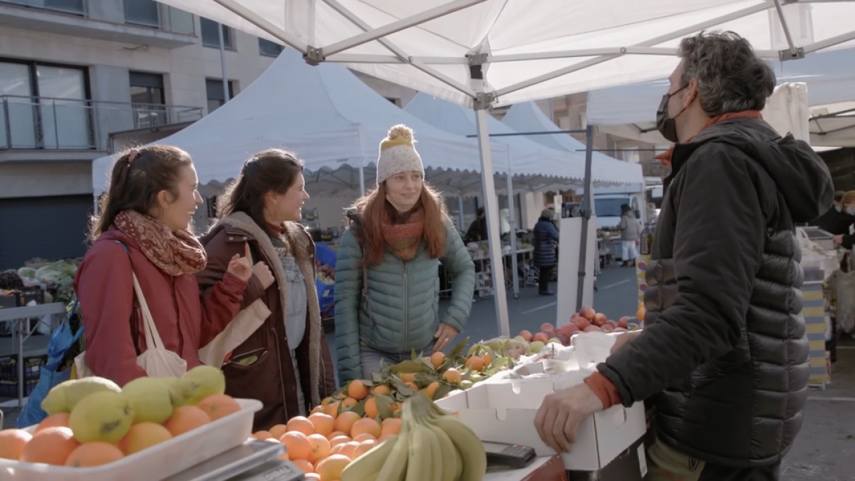 Tres jóvenes clientas en un puesto de fruta, en La Pobla de Segur.