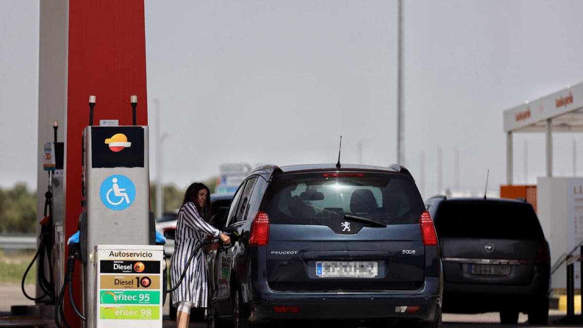 Una mujer repostando combustible  en una estación de servicio.
