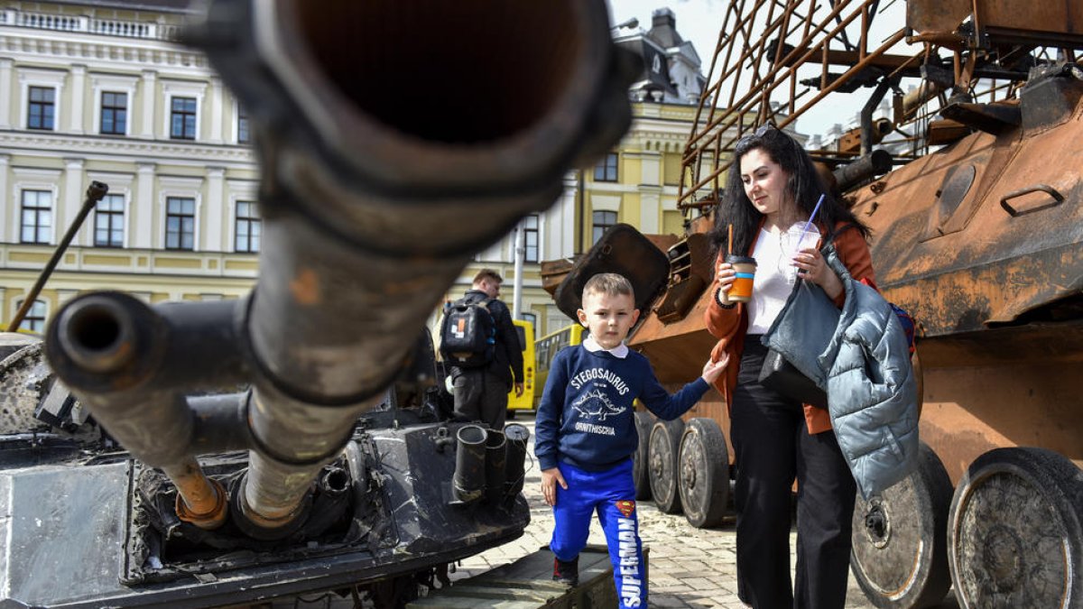 Civils ucraïnesos observen restes militars russes exposades al centre de Kíiv.