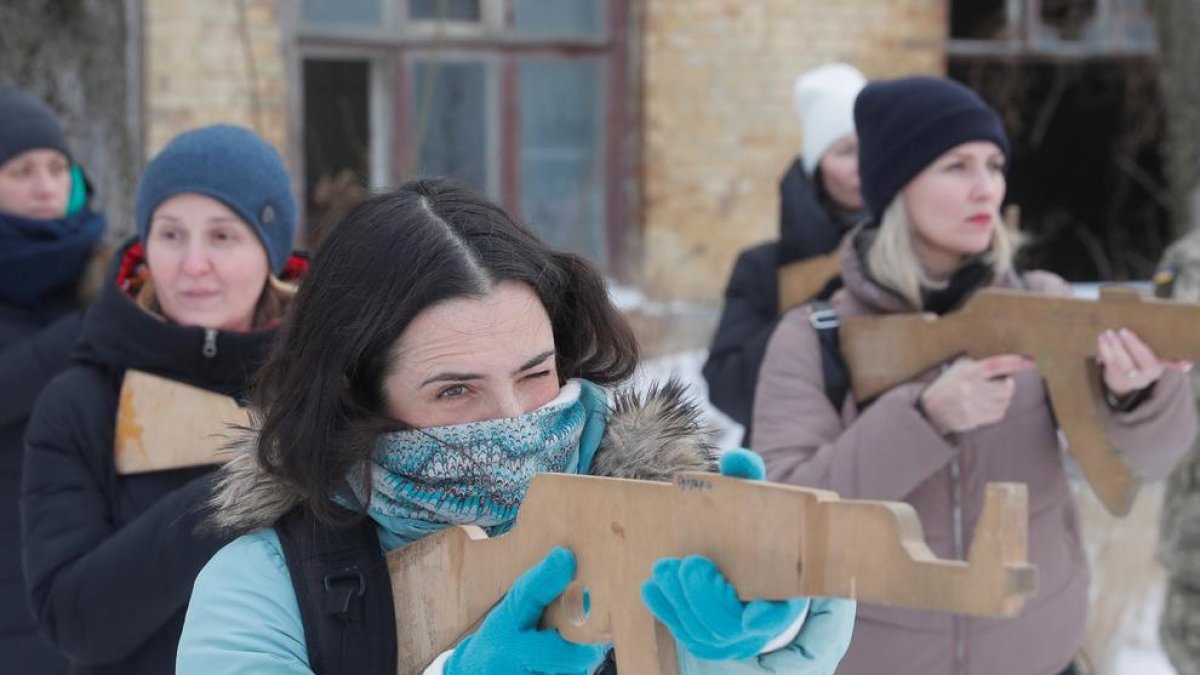 Mujeres ucranianas asisten a un entrenamiento militar abierto en Kiev con armas simuladas de madera.