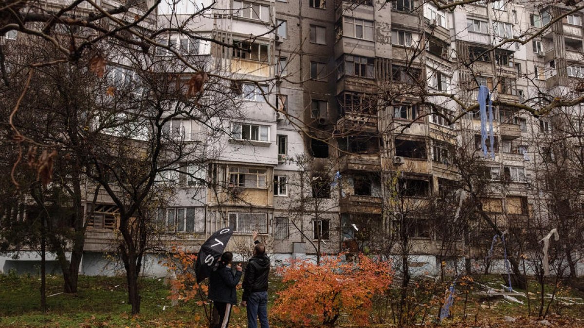 Dos ciudadanos ucranianos delante de un edificio dañado por bombas rusas en Jersón.