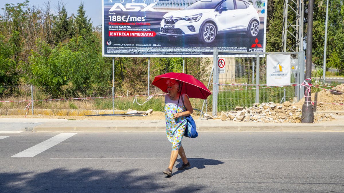 Una dona es protegia ahir del sol amb un paraigua a Lleida ciutat.