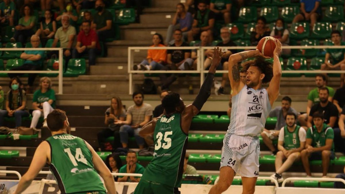 Michael Carrera intenta llançar des d'una posició molt forçada davant de l'intent de tap de Belemene.