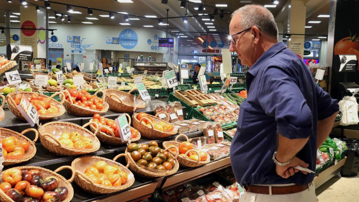 Un hombre observa los precios de los tomates en un supermercado.