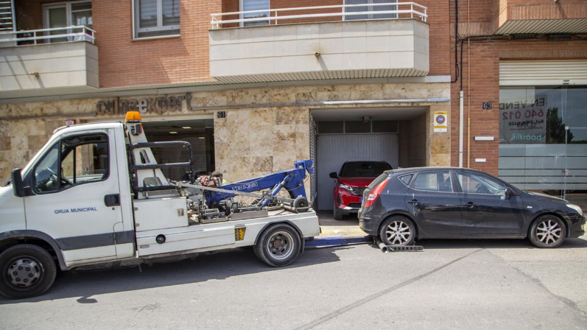 Una grua retira un vehicle estacionat en un gual a Lleida.