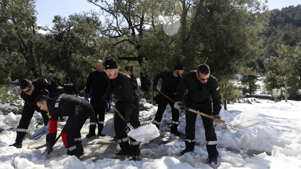 Miembros de la Unidad Militar de Emergencias retiran la nieve a las fueras del monasterio de Lluc.