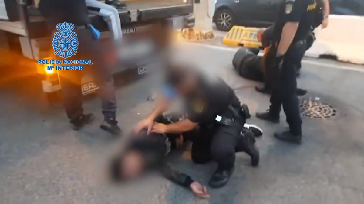 Un agent de la Policia Nacional auxilia un dels migrants.