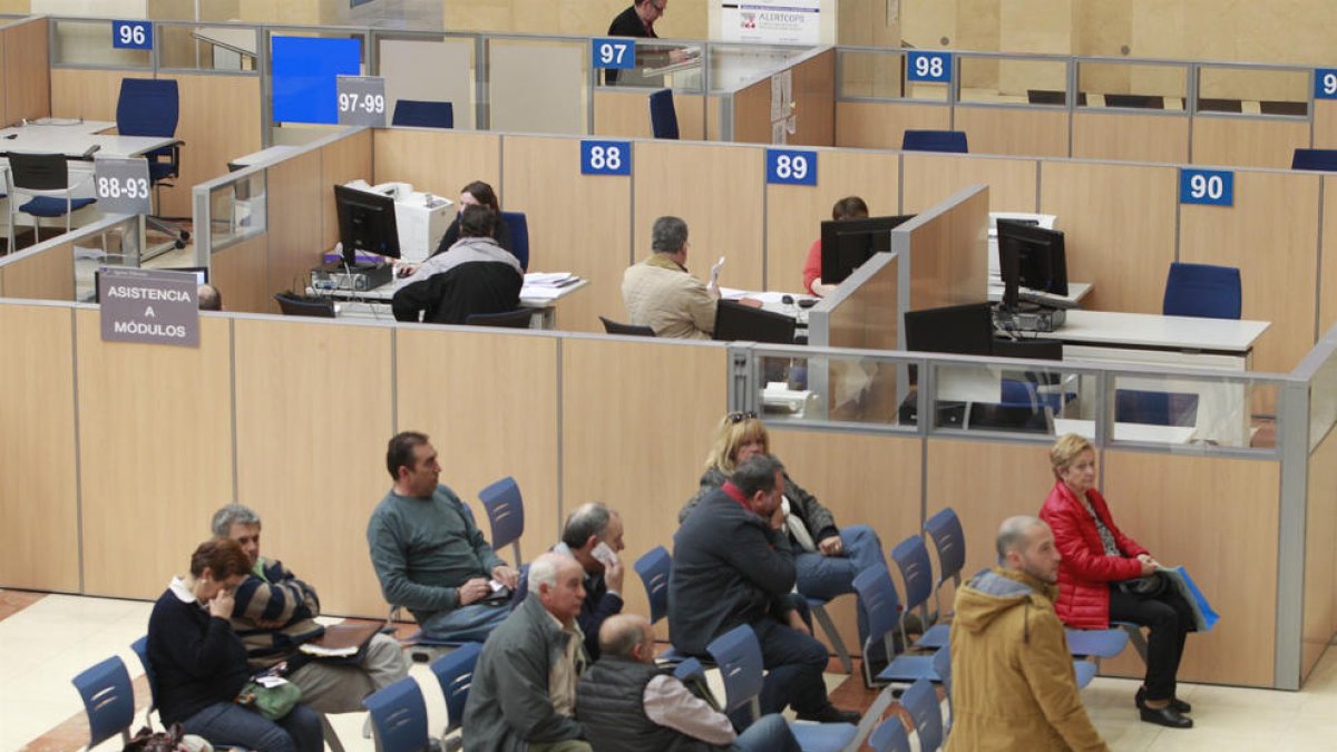 Imatge interior d’una oficina de l’Agència Tributària amb contribuents esperant.