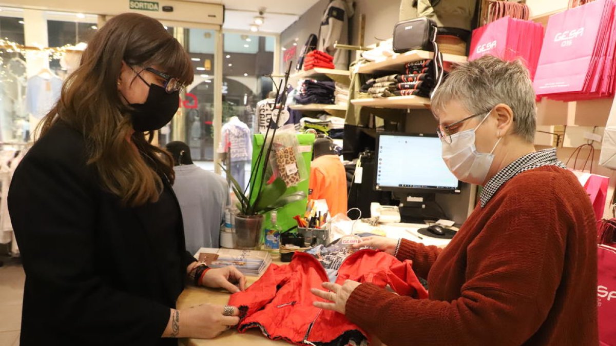 Una comerciante y una clienta en Lleida con mascarilla, obligatoria en interiores.