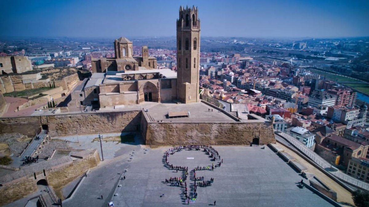 Con carteles lilas decenas de personas formaron el símbolo feminista en la capital del Segrià. A la derecha, la charla celebrada en el parque de Serrallarga.