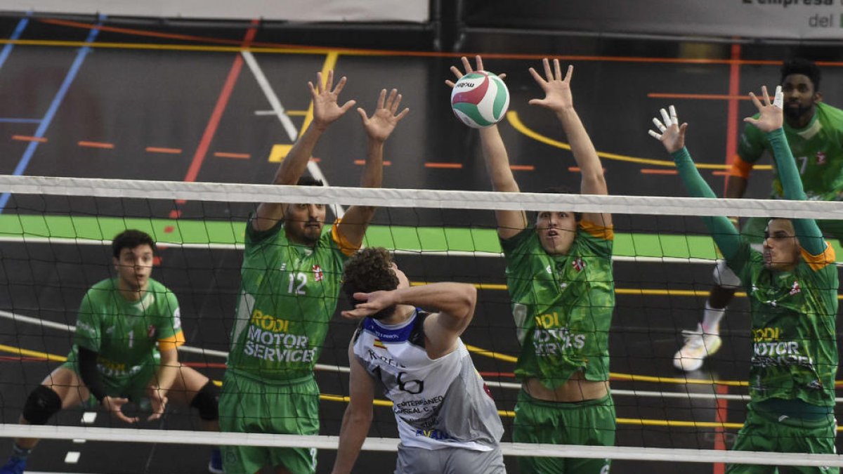 Los jugadores del Rodi Balàfia Vòlei intentan bloquear el ataque rival.