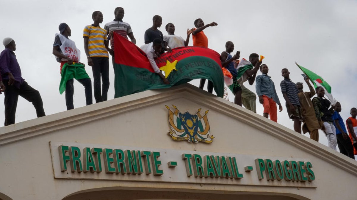 Manifestantes subidos en la entrada a la Asamblea Nacional durante un mitin en Niamey, el jueves.