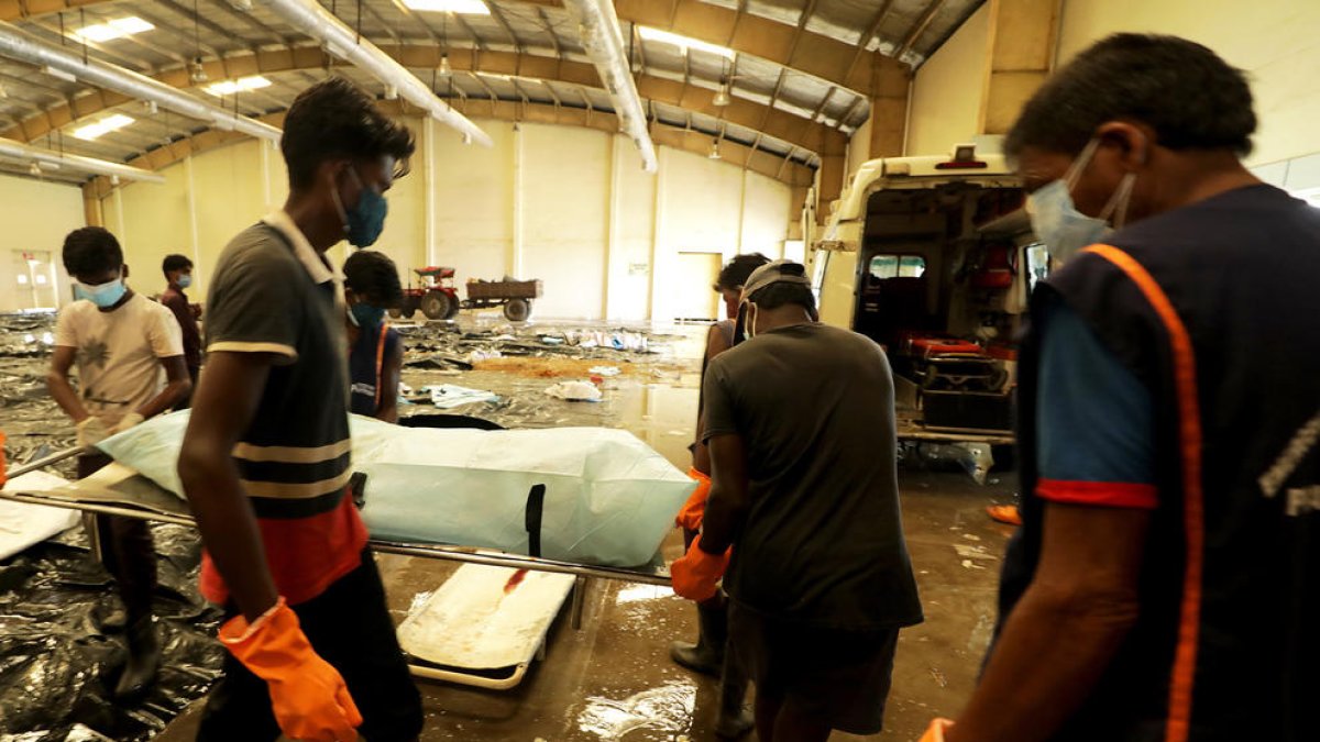 Diverses persones buscant coneguts entre els morts, en un dipòsit de cadàvers.