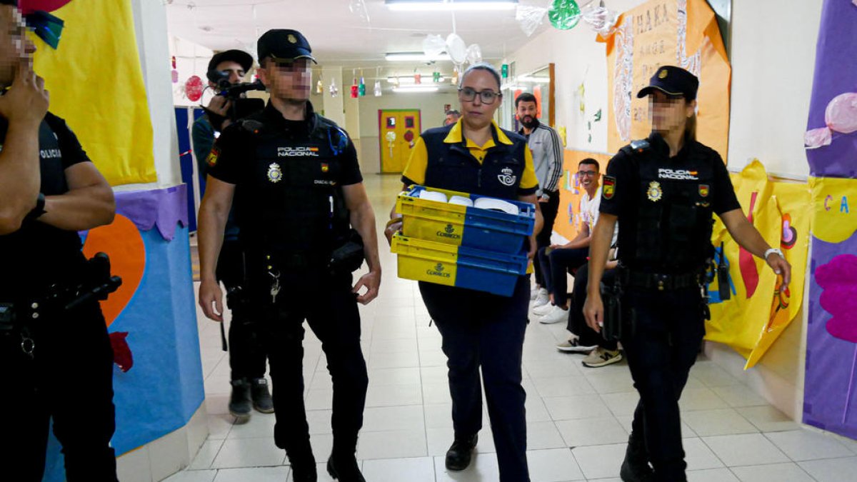 Una funcionària de Correus amb vots escortada per la Policia.
