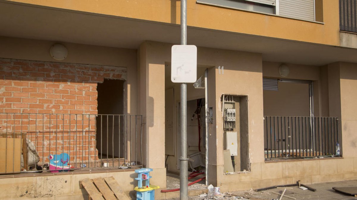 Una entrada al edificio sin puerta, con instalaciones eléctricas rotas y una tapia perforada.