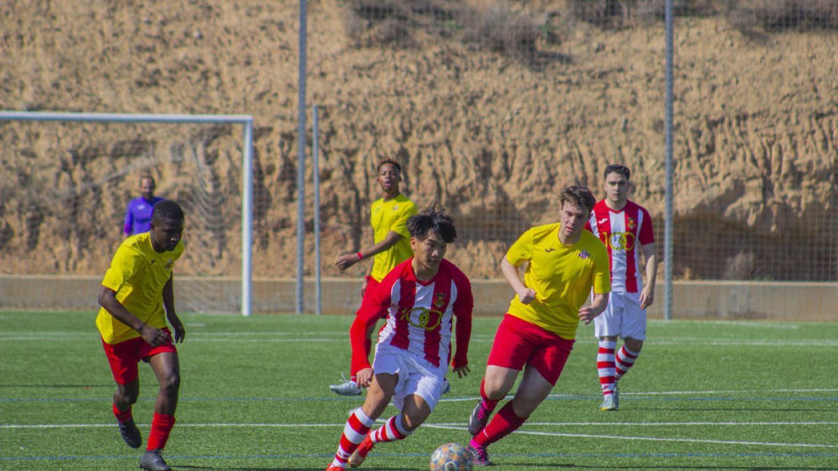 Un jugador local condueix la pilota perseguit per un rival.