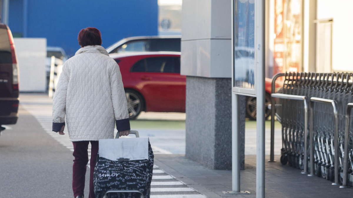 Una dona surt d’un supermercat amb el carretó de comprar