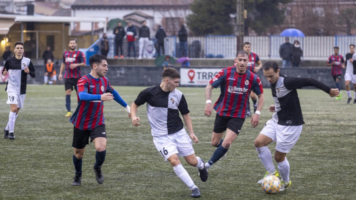 Dos jugadors de l’Horta combinen davant la pressió de dos futbolistes del Tàrrega.