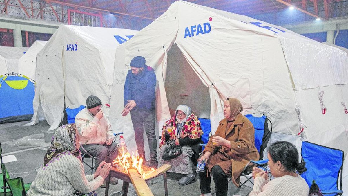 Varios sobrevivientes se calientan cerca de una fogata.