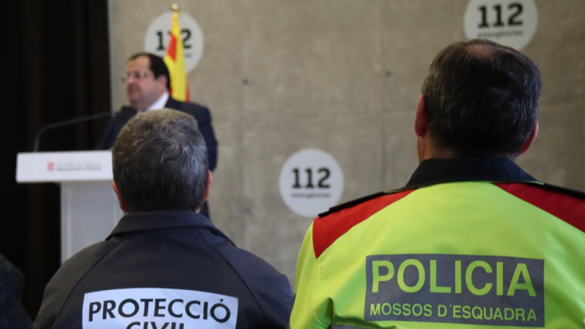 Dos agents de Protecció Civil i dels Mossos d'Esquadra en la roda de premsa d'aquest dimecres sobre les novetats del PLASEQTA, amb el conseller d'Interior, Joan Ignasi Elena, al fons