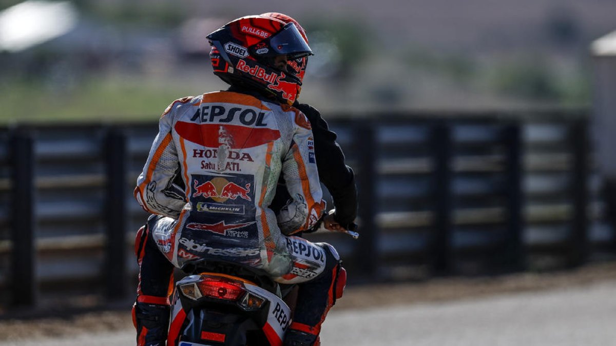 Marc Márquez es llevado por un operario a su box después de sufrir la primera caída tras su regreso.