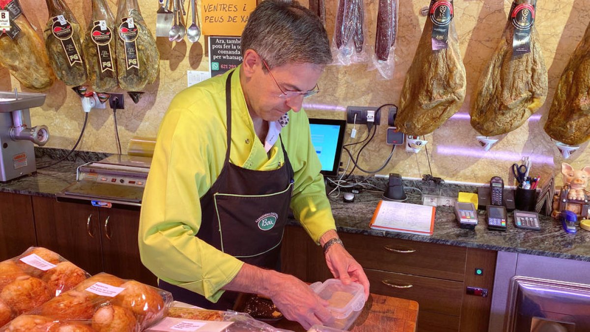 Un carnicero de la Seu d'Urgell, introduciendo parte de la compra de un cliente en una fiambrera.