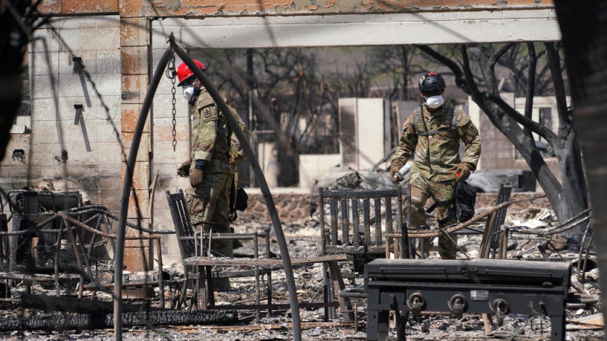 Dos soldats inspeccionen les restes d’un habitatge arrasat pel foc.