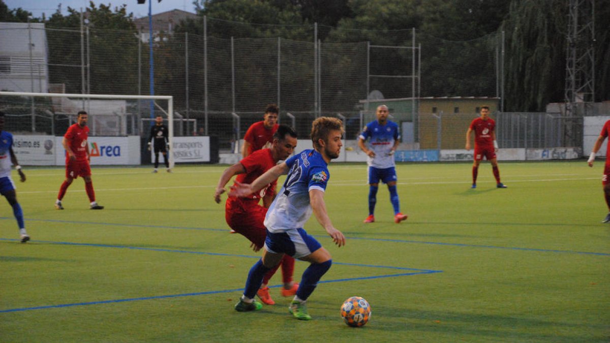 Un jugador del Mollerussa aguanta la possessió davant de la pressió d’un rival de l’Alpicat.