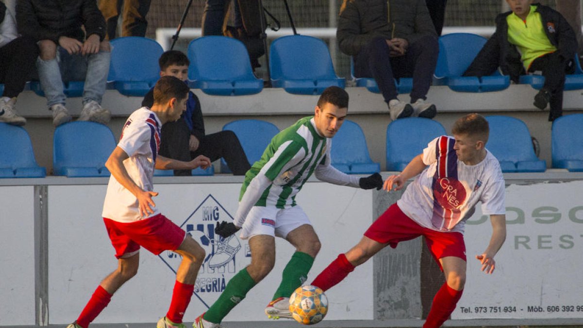 Un jugador de l’Alguaire controla l’esfèric davant de la pressió de dos defenses del Torrefarrera.