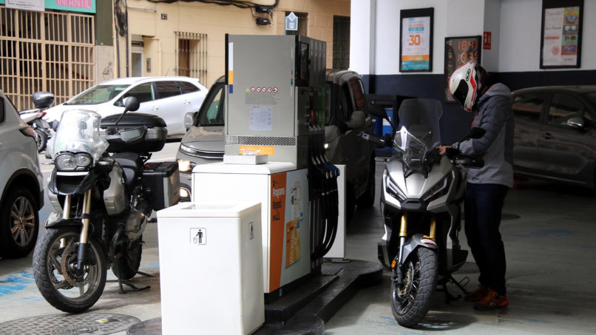 El conductor d'una moto posant combustible a la gasolinera del carrer Legalitat de Barcelona.