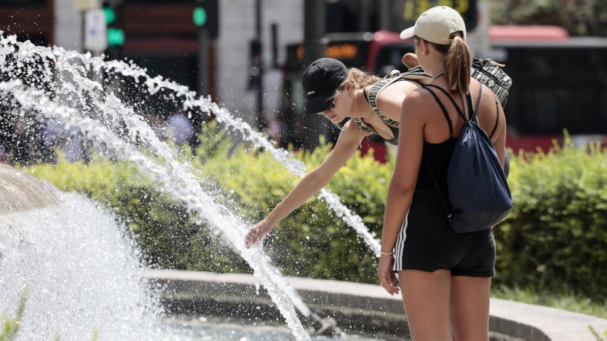 Dos mujeres refrescándose en una fuente en Valencia.