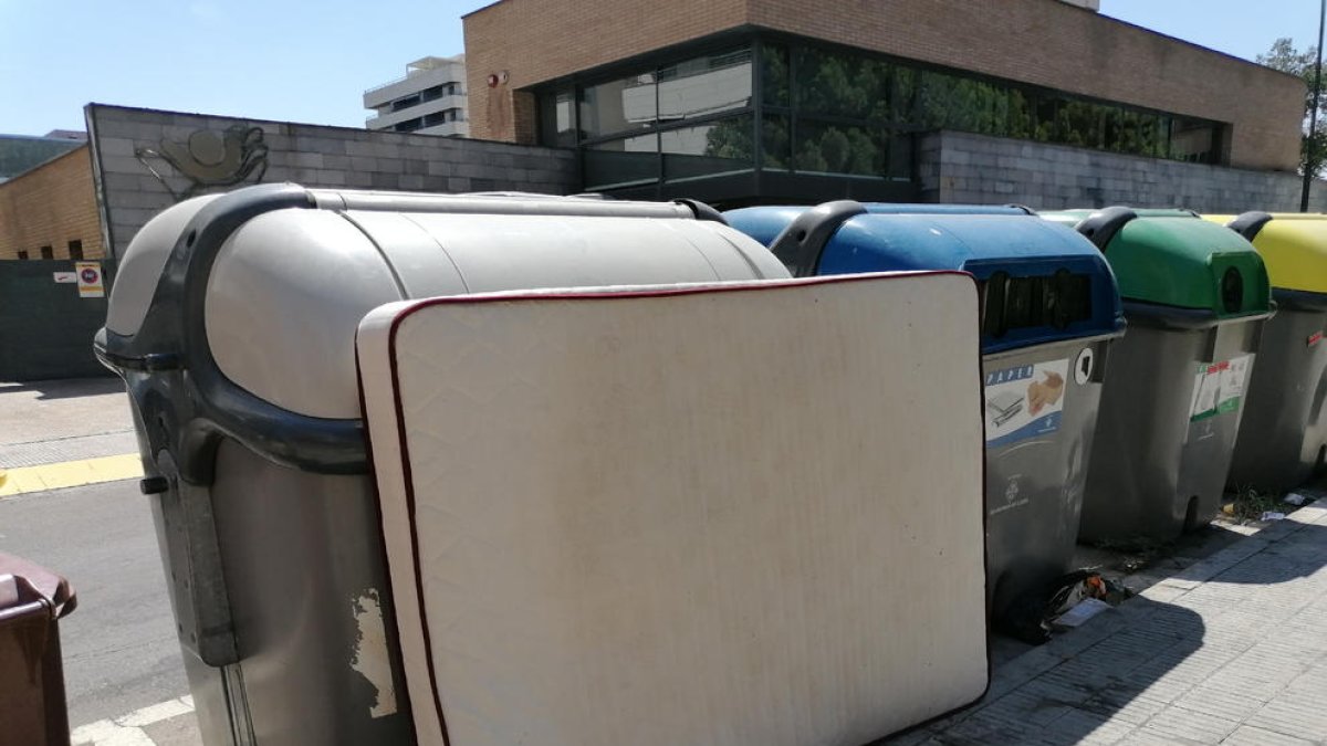 Un colchón abandonado en la calle tapando el acceso a un contenedor en Balàfia.