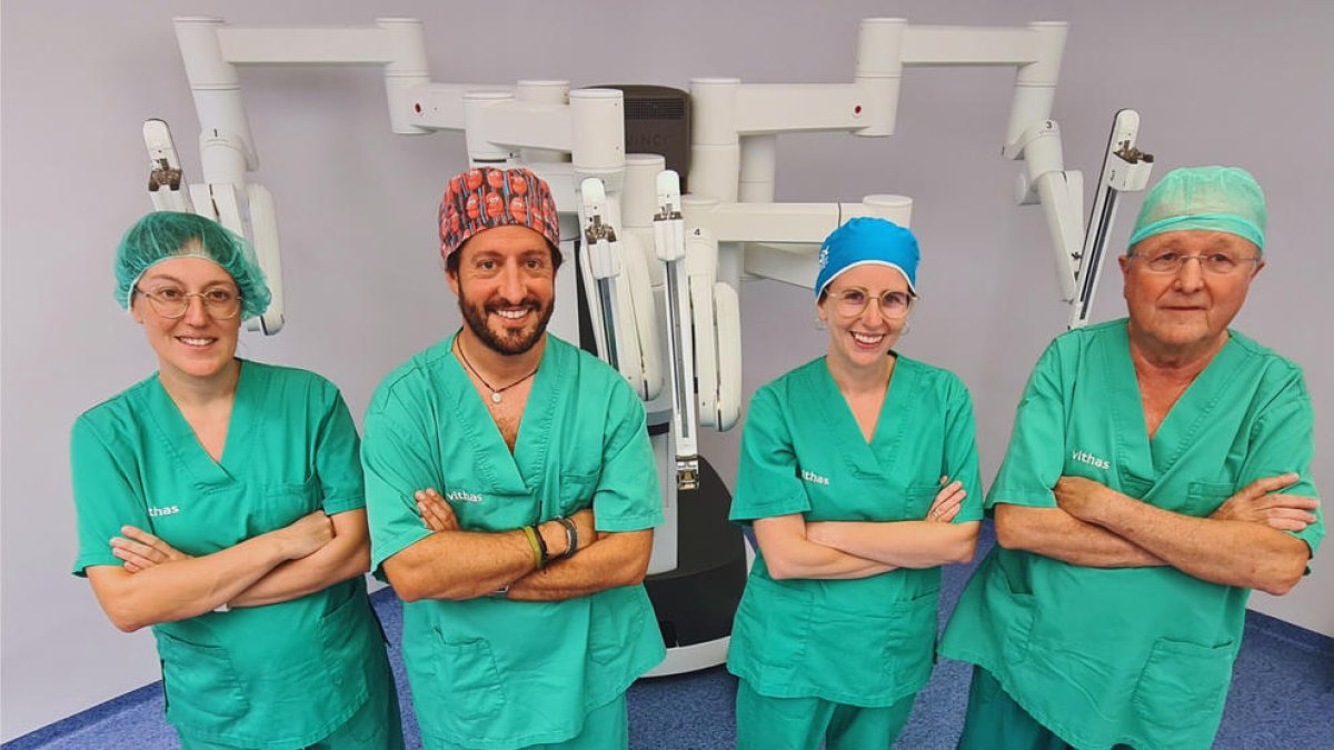 El equipo de urología del hospital Vithas Lleida posa con el robot Da Vinci detrás suyo.
