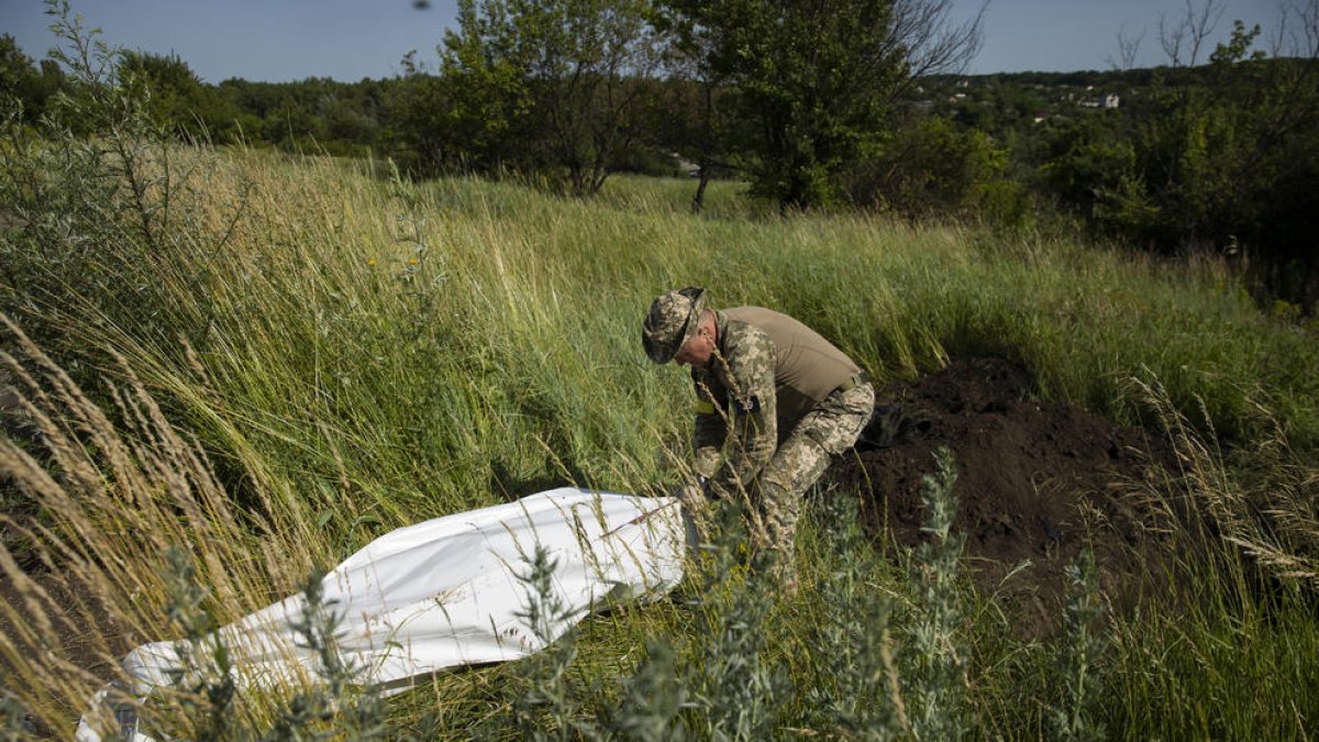 Un militar ucraïnès exhuma cossos de soldats russos a Khàrkiv.