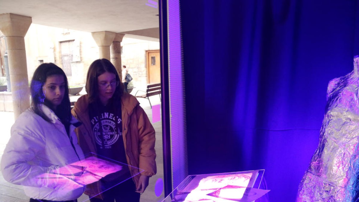 Dos alumnos de la Escuela Ondara de Tàrrega observando una de las creaciones ubicadas en un escaparate vacío de la ciudad.