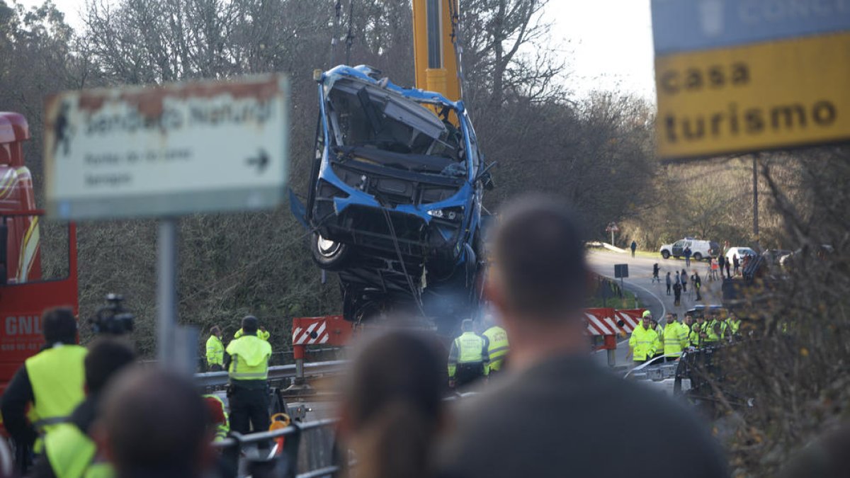 Una grua col·loca l’autobús accidentat sobre el pont.