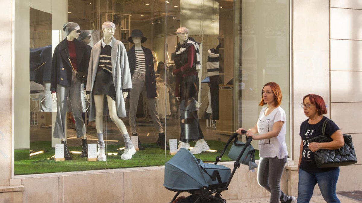 Passejants en màniga curta, ahir davant d’un aparador amb roba de tardor.